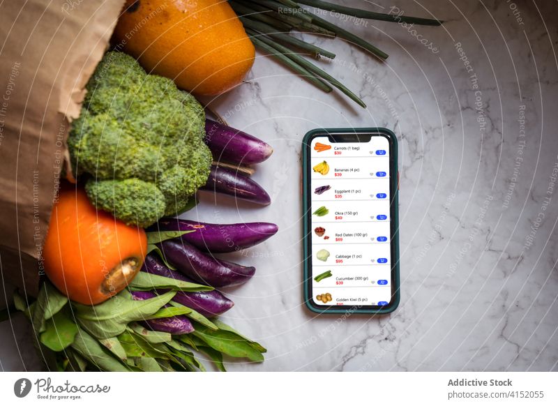 Smartphone und frische Einkäufe auf dem Tisch online Werkstatt App Orden Lebensmittelgeschäft Versand e-Commerce Paket liefern abgelegen Gemüse Frucht