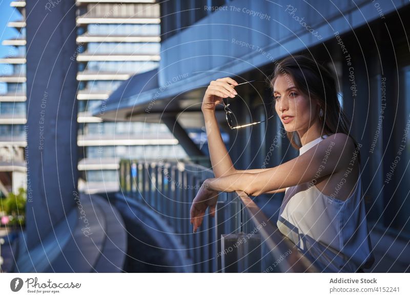 Nachdenkliche junge Frau steht in der Nähe von modernen Gebäude nachdenklich besinnlich einsam Denken urban traurig Zeitgenosse nachdenken Lifestyle träumen
