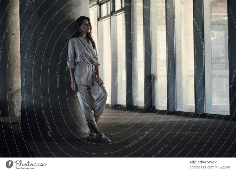 Junge Frau im schicken Anzug steht in der Nähe einer Betonsäule Stil urban Mode besinnlich sich[Akk] entspannen Gebäude nachdenklich Windstille verträumt grau