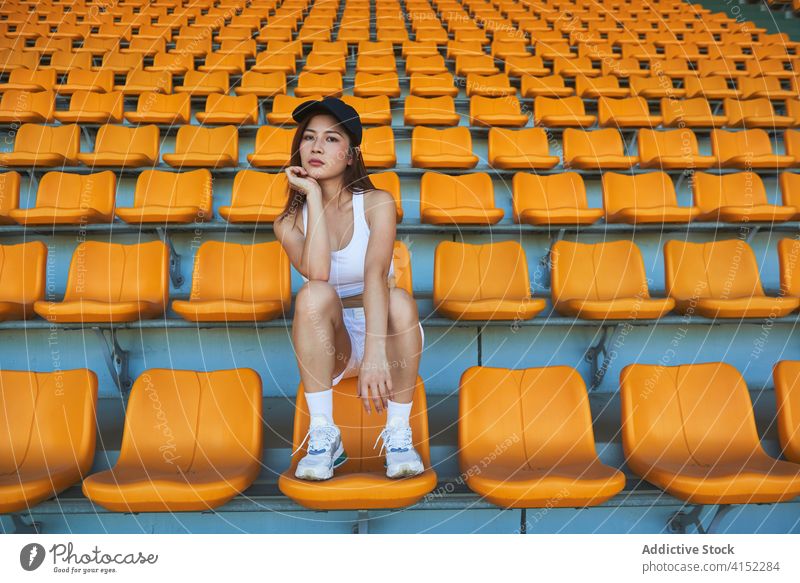 Ruhige Sportlerin im Stadion Frau Sitz sich[Akk] entspannen Training schlanke selbstbewusst Athlet asiatisch ethnisch passen sitzen Pause sportlich Wohlbefinden
