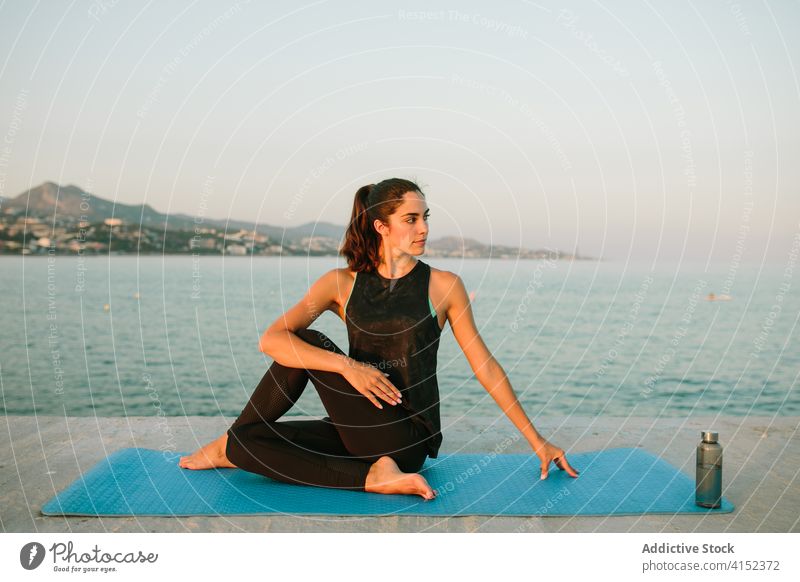 Flexible Frau in der Pose des halben Herrn der Fische Herr der Fische Pose ardha matsyendrasana Yoga beweglich Dehnung Unterlage MEER Pier Körper Abend