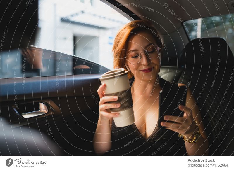 Zufriedene Unternehmerin mit Kaffee und Smartphone im Auto Geschäftsfrau PKW Frau Taxi Arbeitsweg benutzend modern Funktelefon Mobile Anschluss Nachricht Surfen