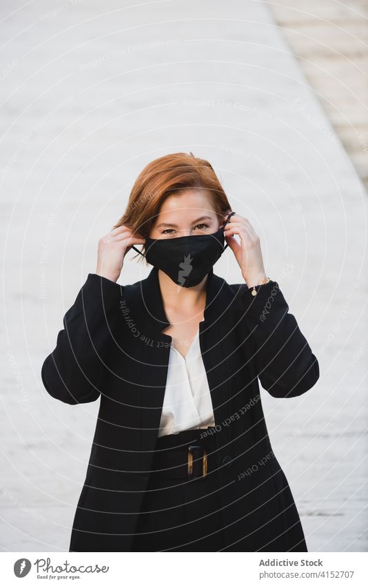 Selbstbewusste Frau im Anzug in der Stadt Geschäftsfrau elegant Unternehmer Bestimmen Sie zuverlässig selbstbewusst Mundschutz Coronavirus behüten Gebäude