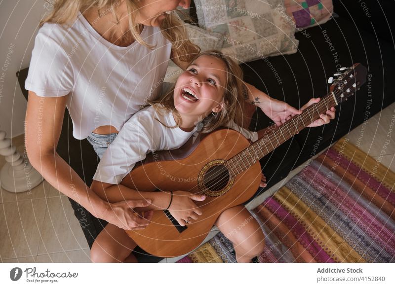 Mädchen, das eine Frau anschaut und anlächelt, die ihr das Gitarrespielen beibringt Musik Bildung Lernen Lehre Lektion Spielen Instrument Musiker Leistung
