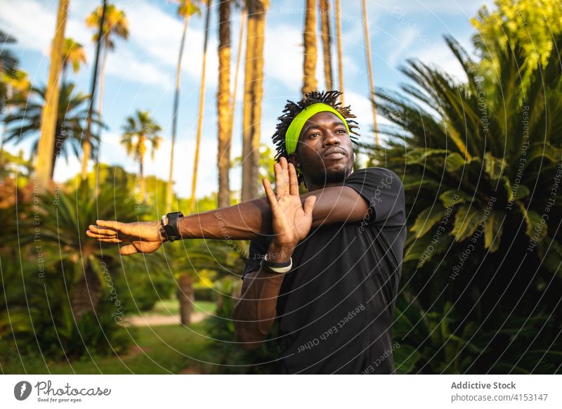 Ethnischer sportlicher Mann beim Training im Park Sportler Dehnung Arme Athlet Übung jung hell Fitness Afroamerikaner schwarz ethnisch Afro-Look männlich