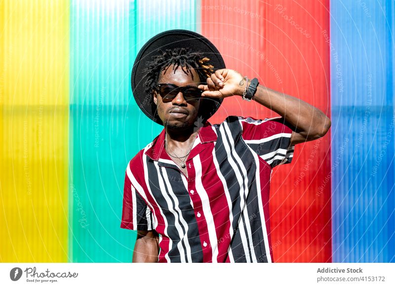 Stilvoller ethnischer Mann mit Sonnenbrille und Hut Mode trendy farbenfroh Streifen jung modern männlich Afroamerikaner schwarz Hipster mehrfarbig selbstbewusst