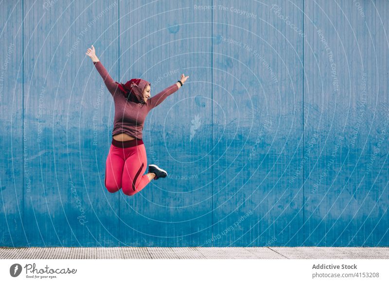 Inhalt Arabische Frau springt in der Stadt feiern Sieg springen Freude erreichen Großstadt sorgenfrei Erfolg arabisch ethnisch Hijab Gebäude blau Wand Tor