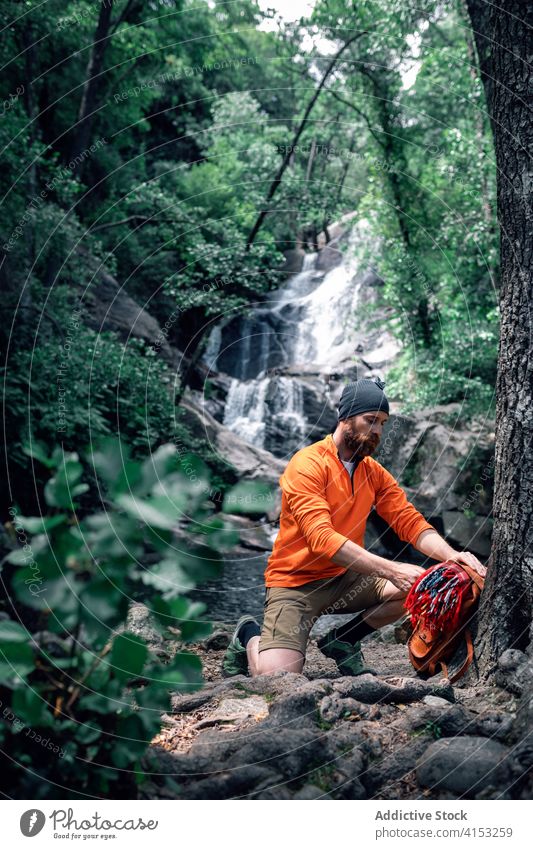 Männlicher Tourist in der Nähe eines reißenden Flusses im Wald Reisender Mann bewundern Urlaub Sommer grün Wälder Abenteuer männlich Rucksack Felsen reisen