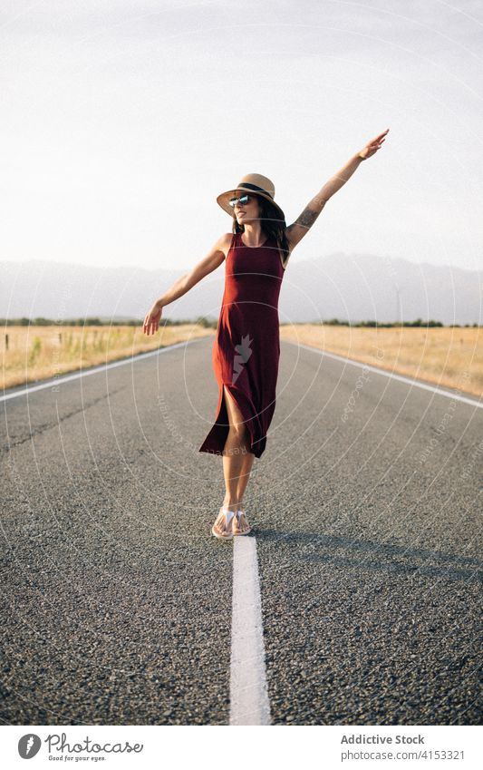 Zufriedene Frau auf der Straße im Sommer sorgenfrei Reisender genießen Urlaub Freiheit Lächeln Spaziergang leer Fahrbahn Kleid Sonnenhut Ausflug Glück Feiertag