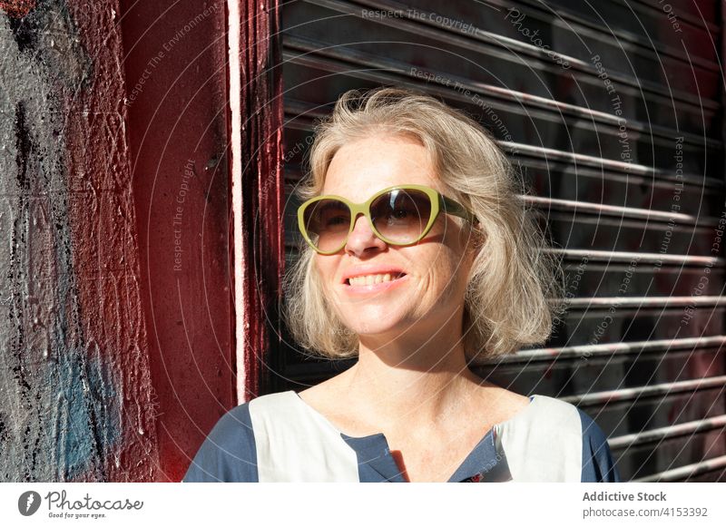 Stilvolle Frau auf der Straße in der Stadt Graffiti Wand Großstadt trendy sonnig Wochenende genießen Mode urban heiter Lächeln Glück sich[Akk] entspannen Freude