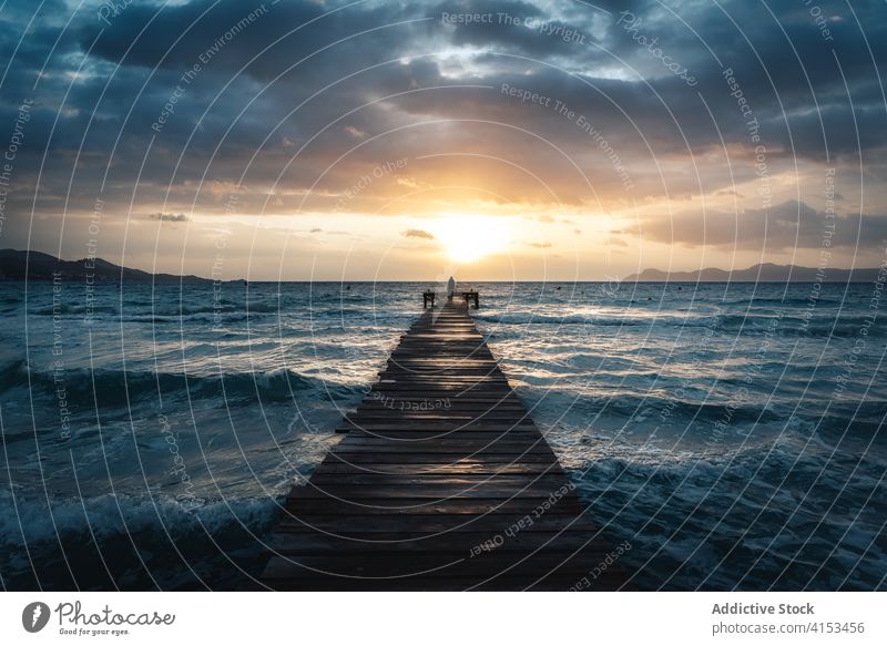 Anonyme Person steht auf einem Holzsteg im Meer bei Sonnenuntergang hölzern Pier MEER Meereslandschaft stürmisch Wasser Kai wolkig stehen dramatisch