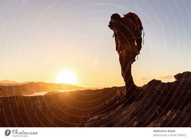 Männlicher Wanderer mit Rucksack im Hochlandtal Reisender Hügel Mann Berge u. Gebirge bewundern Tal stehen erkunden Sonnenuntergang Himmel Urlaub Kamm