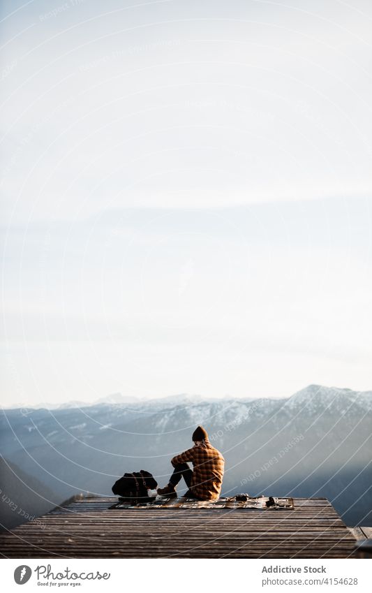 Reisender Mann sitzt auf einem Hügel und bewundert die Aussicht auf die Berge Aussichtspunkt Berge u. Gebirge Tourist Landschaft Kamm Morgen