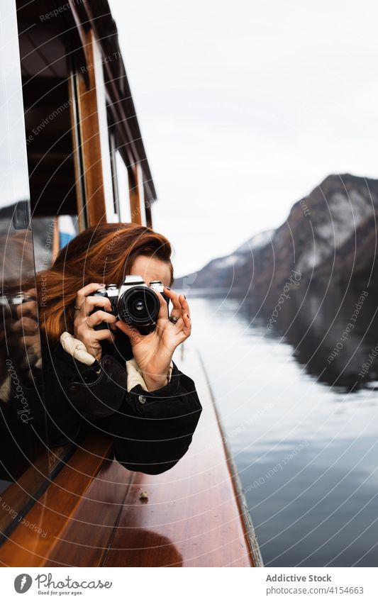 Frau fotografiert vom Boot aus während eines Ausflugs auf dem See Fotoapparat reisen Fenster Fotograf fotografieren Herbst Natur Berge u. Gebirge Reise