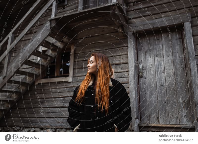 Junge Frau steht in der Nähe einer verwitterten Holzhütte Gebäude hölzern gealtert Kabine Haus Landschaft Tür Laufmasche jung Tourist Nutzholz schäbig
