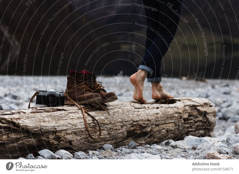 Barfüßiger Reisender, der auf einem Holzstamm läuft Frau Barfuß Totholz Ufer hölzern Fotoapparat Stiefel Bein Abenteuer Fotografie sorgenfrei Erholung kalt
