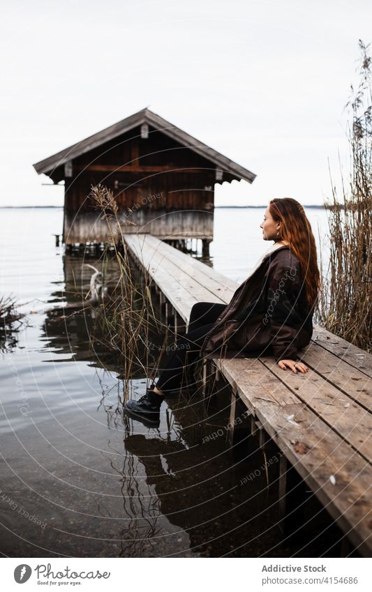 Einsame Frau steht auf Holzsteg am See Pier Baracke Herbst trist einsam Reisender schäbig Windstille ruhig Natur reisen Tourismus Deutschland Österreich hölzern
