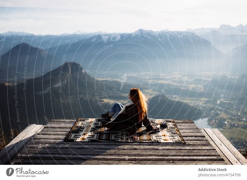 Reisende Frau auf Holzterrasse im Hochland Aussichtspunkt Berge u. Gebirge Morgen Reisender Sitzen Nebel Sonnenstrahlen ruhig genießen Deutschland Österreich