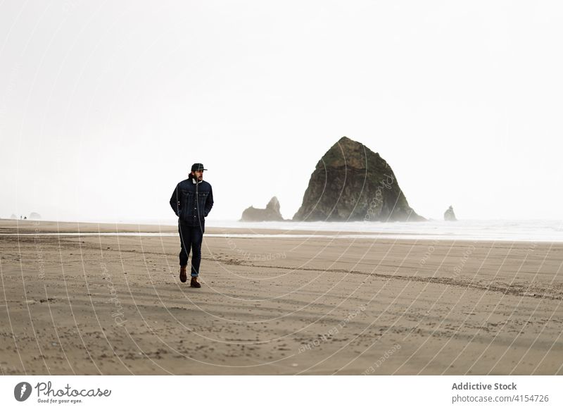 Männlicher Tourist am Meer an einem bewölkten Tag Mann Meeresufer Spaziergang wolkig Meereslandschaft trist bedeckt MEER schäumen Natur USA Vereinigte Staaten