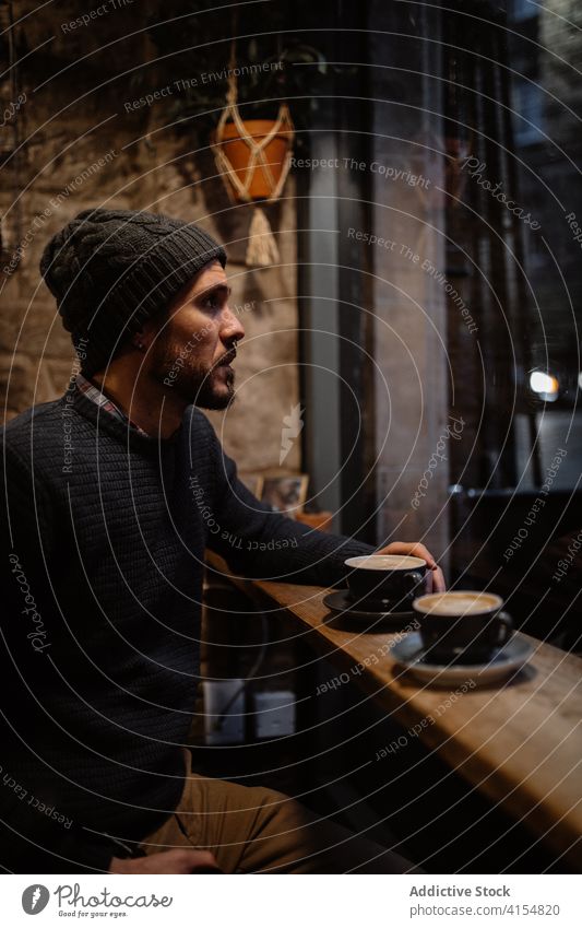 Ruhiger Mann sitzt in gemütlichem Café im Herbst genießen Kaffee Atmosphäre Innenbereich warm Windstille männlich Abfertigungsschalter Hut Pullover trinken