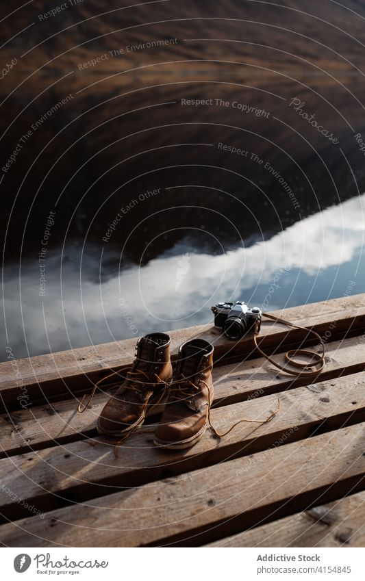 Trekkingstiefel und alte Fotokamera auf dem Steg Stiefel reisen Fotoapparat altehrwürdig Pier retro Atmosphäre Schuhe dreckig Schottisches Hochland Schottland