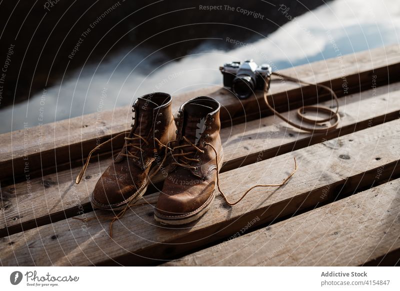 Trekkingstiefel und alte Fotokamera auf dem Pier Stiefel reisen Fotoapparat altehrwürdig retro Atmosphäre Schuhe dreckig Schottisches Hochland Schottland