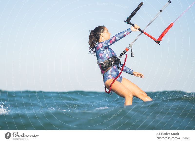 Weiblicher Kite-Surfer reitet auf dem Brett im Meer Milan Brandung Frau Mitfahrgelegenheit winken MEER platschen Sommer professionell Badeanzug passen Erholung