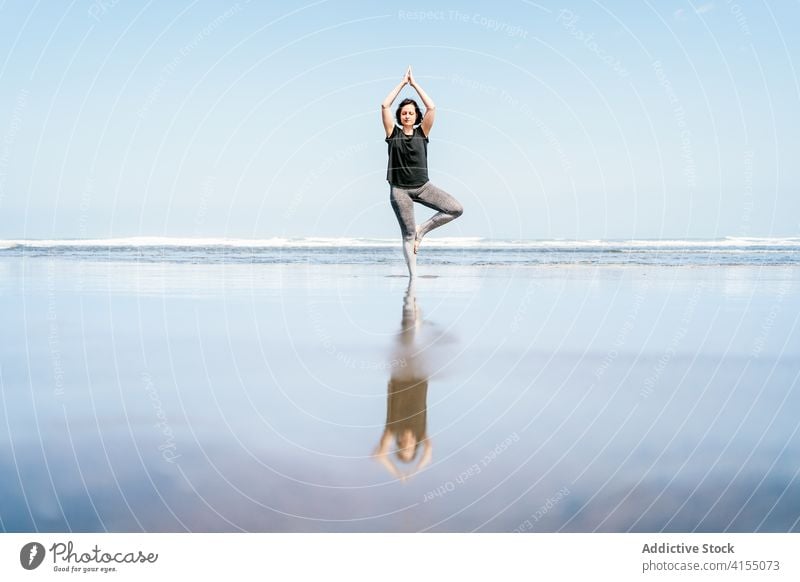Junge Frau in balancierenden Yoga-Asana stehend am Strand MEER üben Pose Baum vrksasana Gleichgewicht Windstille Meeresufer Harmonie Augen geschlossen Wellness