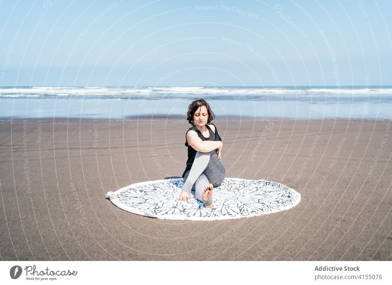 Schlanke Frau in sitzender Twist-Yoga-Pose am Strand MEER üben Asana Halbherr der Fische ardha matsyendrasana verdrehen Gleichgewicht Windstille Meeresufer