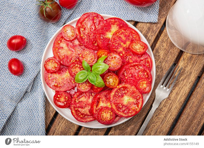 Draufsicht auf Tomatensalat und Basilikumblätter auf einem Teller. Mediterranes Essen Salatbeilage Kirsche frisch Küche Diät Lebensmittel Frische Gesundheit