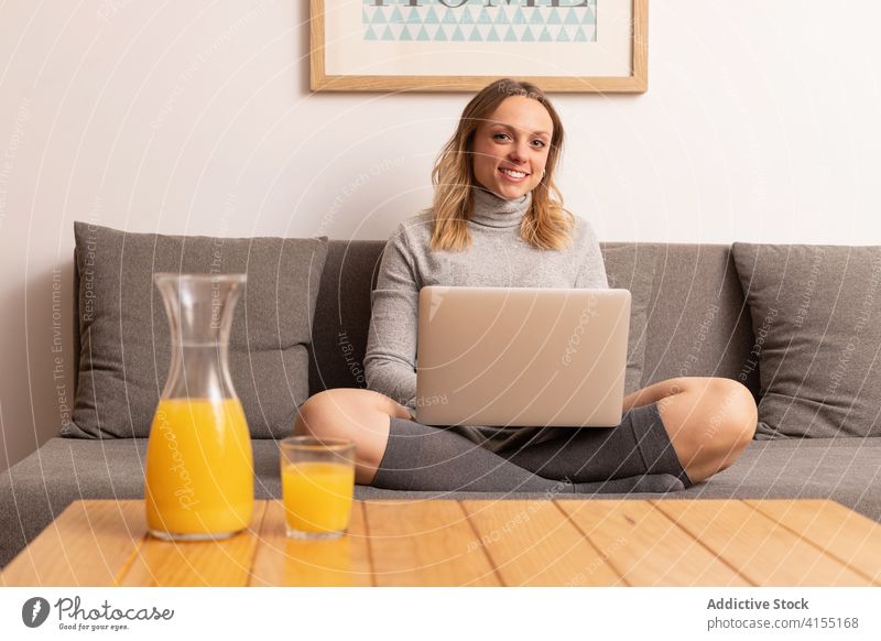 Fröhliche Frau arbeitet zu Hause am Laptop abgelegen Projekt freiberuflich Arbeit Lächeln heimwärts Browsen Unternehmer Netbook Surfen online Job Liege