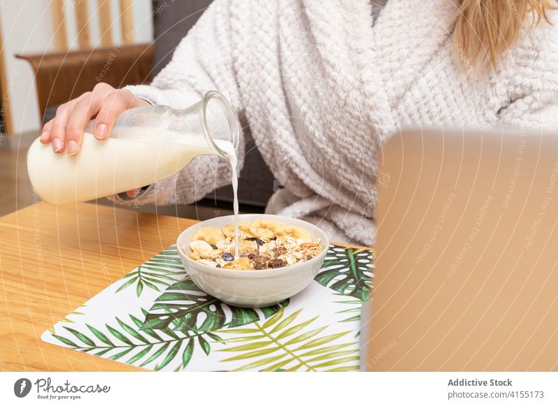 Anonyme Frau beim Frühstück zu Hause Schalen & Schüsseln Müsli melken eingießen Morgen Ernährung gesunde Ernährung heimwärts lecker Tisch Laptop Lebensmittel