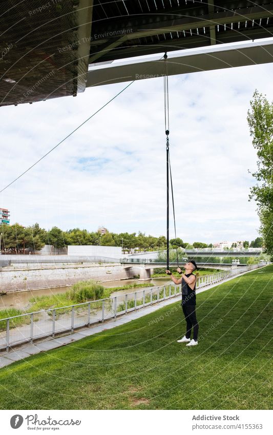 Männlicher Sportler mit Luftgurten im Park Antenne Gurt Mann Turner prüfen Training vorbereiten Sicherheit Seil männlich Brücke Athlet Aktivität Wellness passen