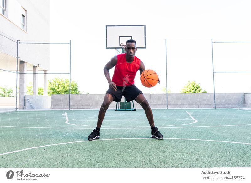 Konzentrierter schwarzer Mann spielt Basketball auf dem Platz Spieler spielen Ball Sportpark Spielplatz ernst Taktik Fokus männlich Afroamerikaner ethnisch