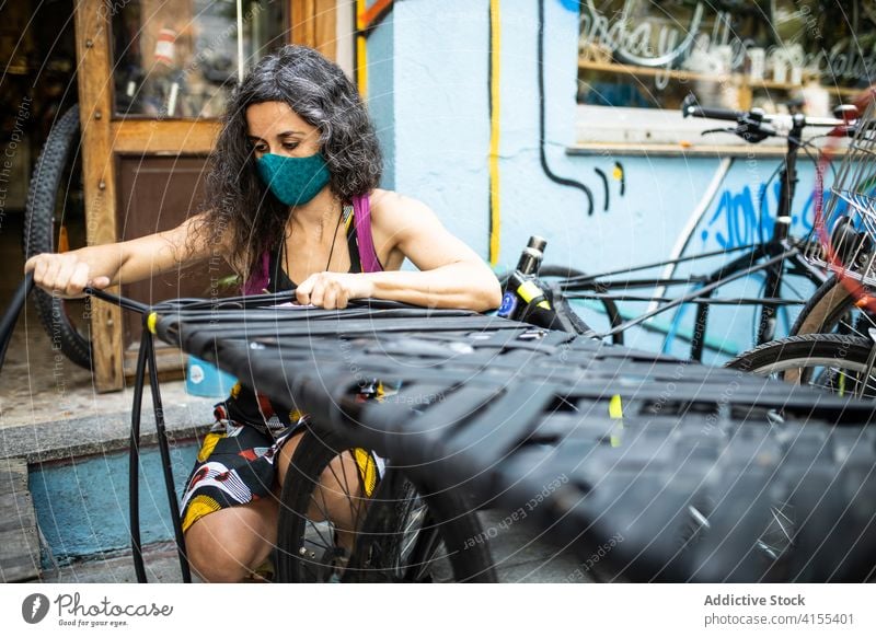 Mechanikerin bei der Arbeit in einer Fahrradwerkstatt Werkstatt Reparatur Frau fixieren Dienst Flugzeugwartung Gurt Reifen Beruf ethnisch professionell Job