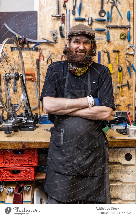 Positiver reifer Handwerker in der Werkstatt Heimwerker Mechaniker Kunsthandwerker Vollbart positiv Porträt Beruf selbstbewusst freundlich Lächeln Fahrrad