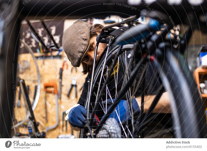 Reparateur repariert Fahrradrad in der Werkstatt Reparatur Mann Mechaniker Rad Speiche fixieren Flugzeugwartung Beruf Dienst männlich Vollbart reif