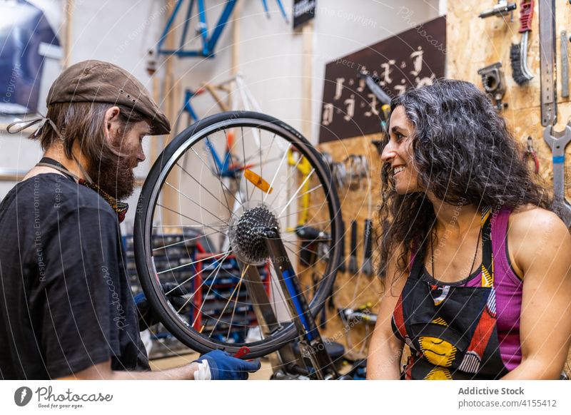Zwei Mechaniker, die zusammen im Fahrradservice arbeiten Paar Werkstatt Besitzer Kleinunternehmen Dienst fixieren Reparatur Rad heiter Glück Beruf Wehen