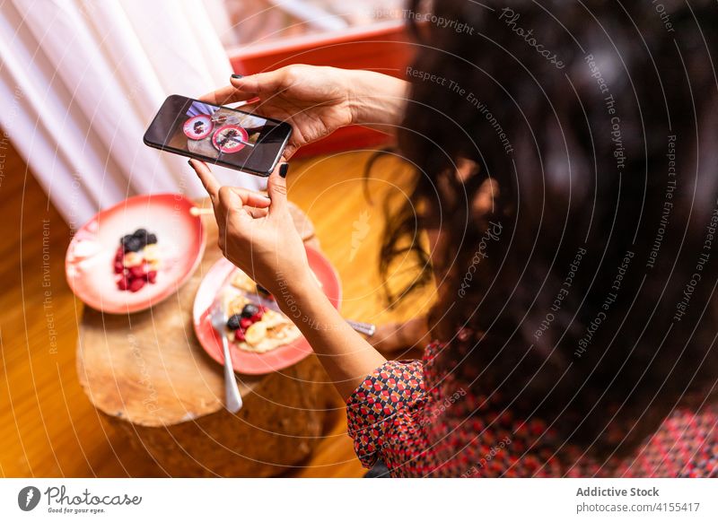 Frau benutzt Smartphone beim Frühstück Pfannkuchen Lächeln frisch geschmackvoll Gesundheit Frucht lecker Himbeeren Handy Apparatur Liebling Glück organisch Foto