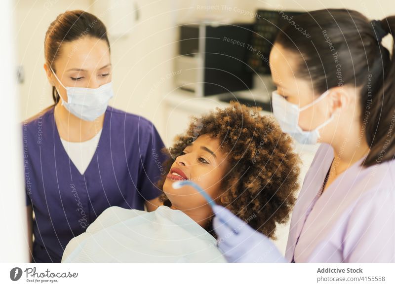 Zahnärzte heilen Zähne einer schwarzen Frau Zahnarzt geduldig Aushärten Überprüfung Klinik Assistent Spiegel bohren Sog Gerät Uniform dental Medizin Behandlung