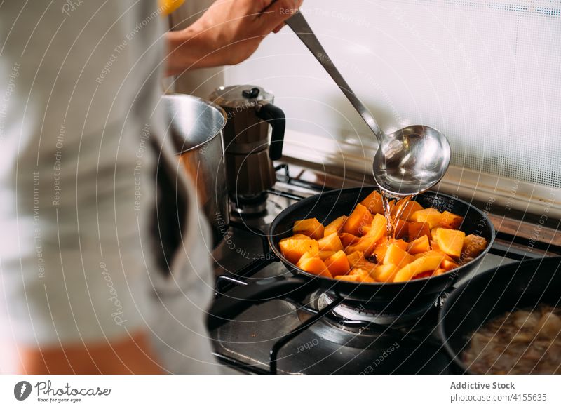 Hausfrau bereitet Kürbis für Suppe vor Koch vorbereiten schmoren Wasser eingießen Gemüse Bestandteil Lebensmittel Küche hinzufügen Frau Rezept kulinarisch