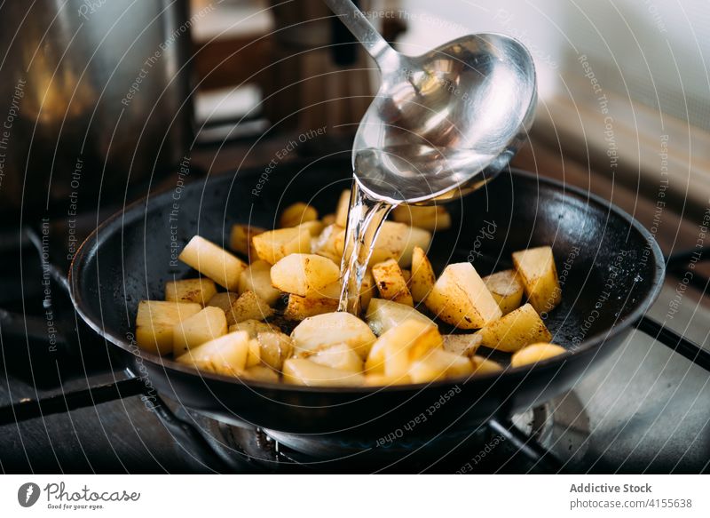 Frau beim Kochen einer Gemüsesuppe mit Kürbis, Kartoffeln und Zwiebeln braten Pfanne vorbereiten Löffel Wasser Bestandteil eingießen rühren Lebensmittel Rezept