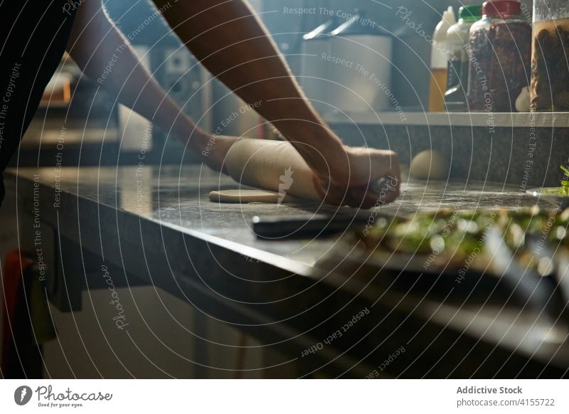 Anonymer Koch, der Teig für Gebäck ausrollt Mann Küchenchef rollen Teigwaren Nudelholz Tisch Pizza Bestandteil Prozess männlich vorbereiten Dehnung frisch