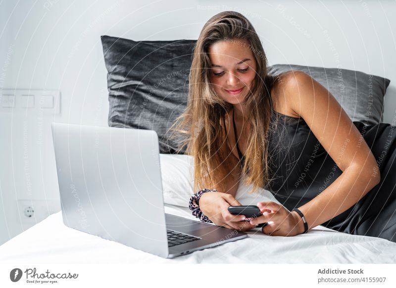 Zufriedene Frau auf dem Bett am Morgen Smartphone Browsen Nachtwäsche LAZY Lügen Schlafzimmer benutzend ruhen weich Komfort Gerät Apparatur Internet gemütlich
