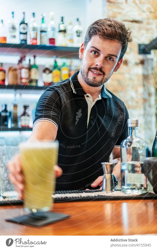 Crop Barmann bereitet Cocktail am Tresen alkoholfrei vorbereiten Barkeeper Frucht Kiwi Garnierung kalt Erfrischung männlich Glas Scheibe trinken Getränk lecker