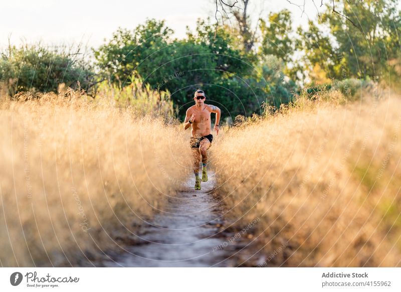 Energetischer Sportler, der auf einem Weg in der Natur läuft stark Energie laufen Kraft Athlet ohne Hemd Läufer Mann Jogger Training Ausdauer Bewegung männlich
