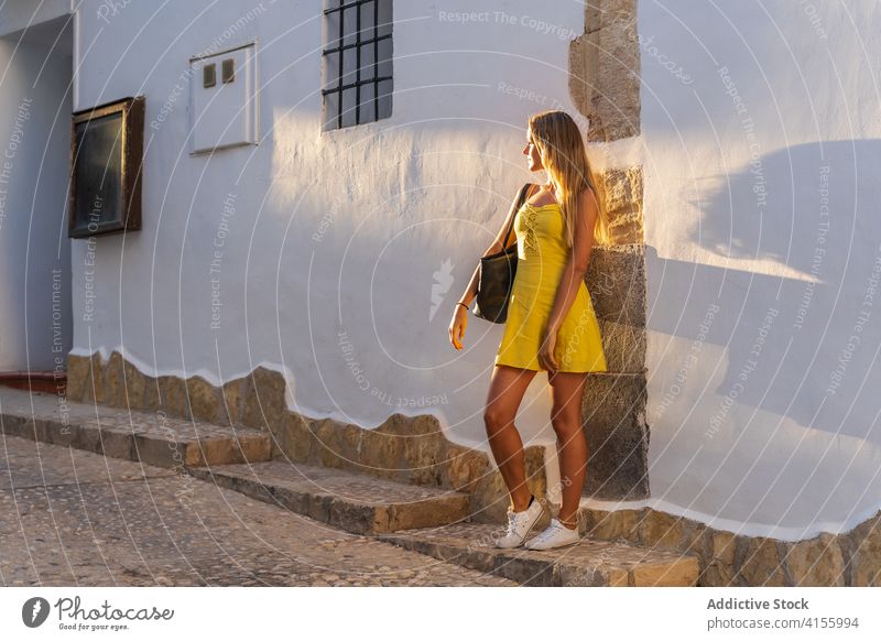 Zufriedene Frau im Kleid in der Nähe eines Gebäudes Großstadt Tourist Sommer Sonnenlicht Urlaub historisch Stadt sonnig Wand Stein reisen Straße Freude Feiertag