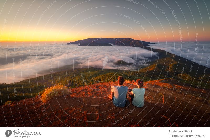 Verliebtes Paar auf einem Hügel im Hochland reisen Berge u. Gebirge bewundern genießen wolkig Partnerschaft Reisender spektakulär Angebot Umarmen sitzen
