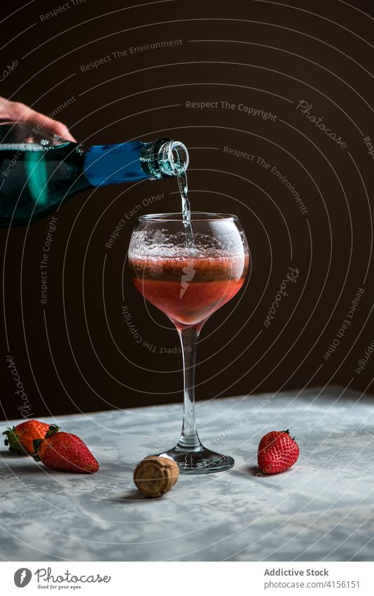 Crop-Frau gießt Getränk in Glas Alkohol eingießen trinken Erdbeeren Cocktail süß Tisch lecker frisch vorbereiten liquide geschmackvoll Prozess Bestandteil
