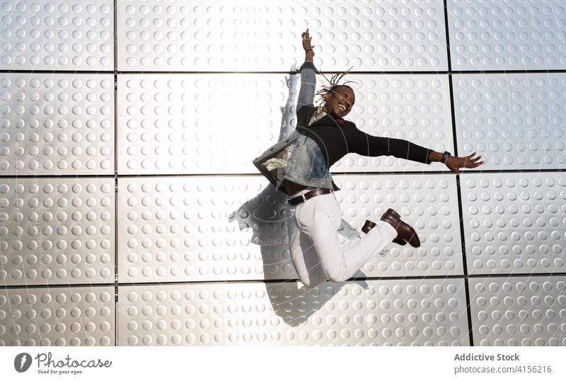 Stilvoller schwarzer Mann springt in der Nähe eines Gebäudes in der Stadt Geschäftsmann springen Moment Großstadt Unternehmer Manager sorgenfrei Freiheit